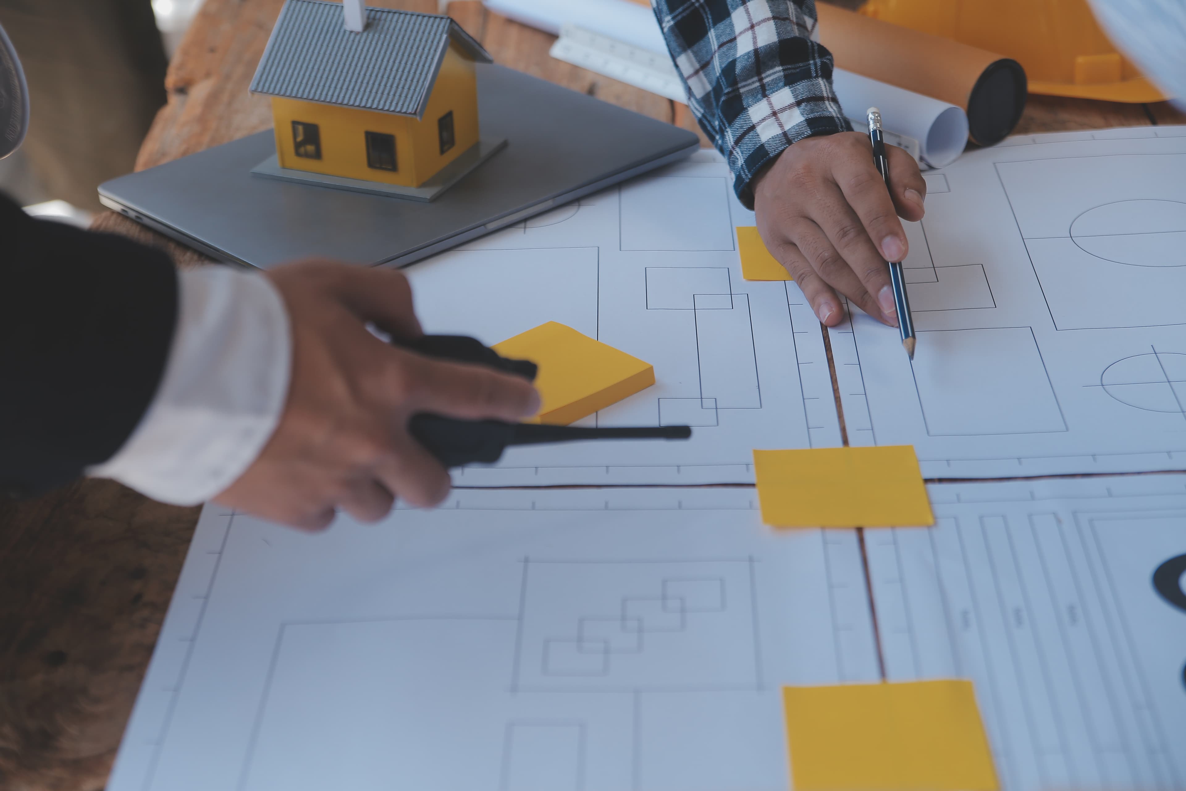 Architects planning a second-storey addition in Coomera, reviewing blueprints and building models.