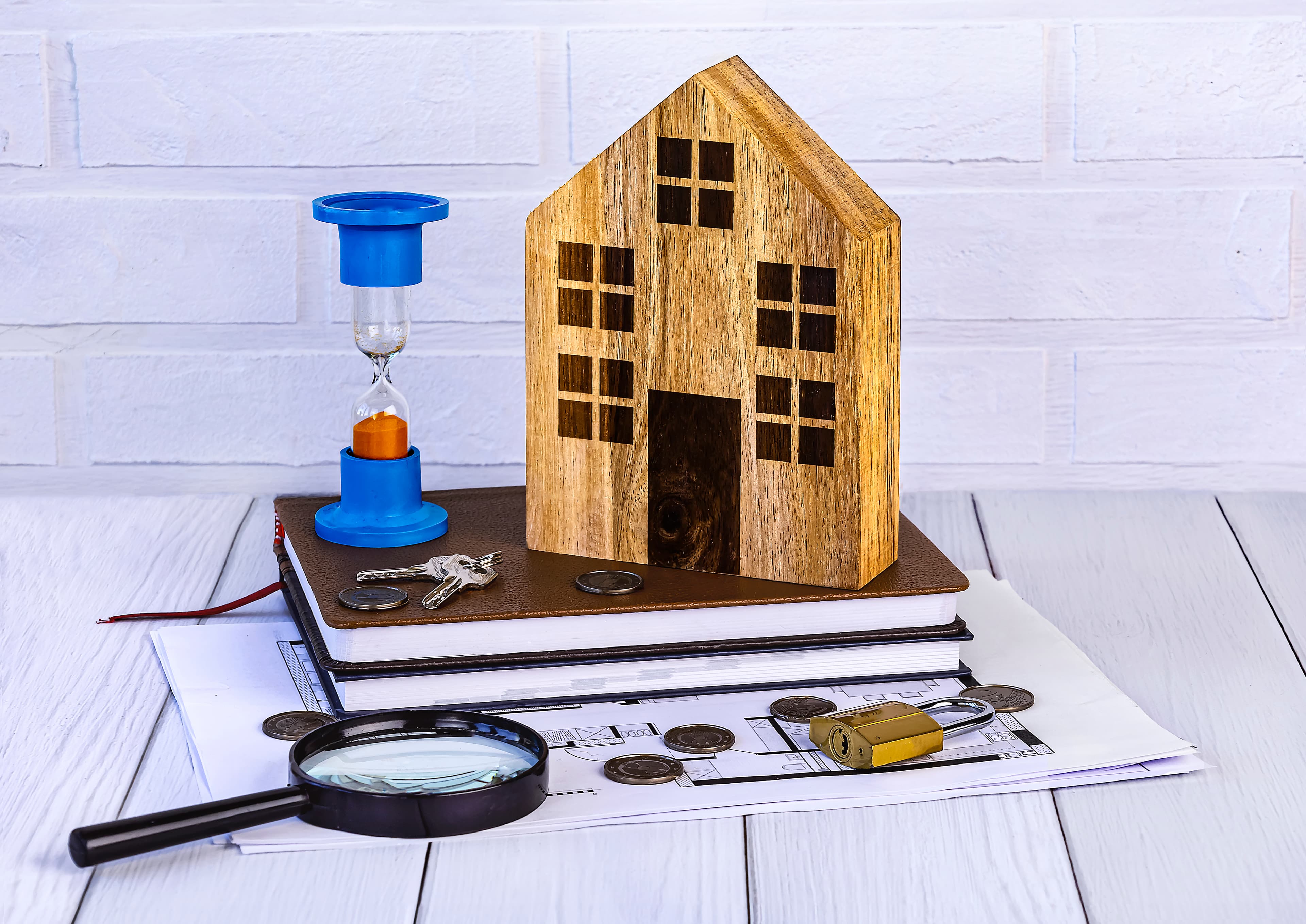 Wooden house model with coins, plans, and magnifying glass illustrating home renovation finance options.