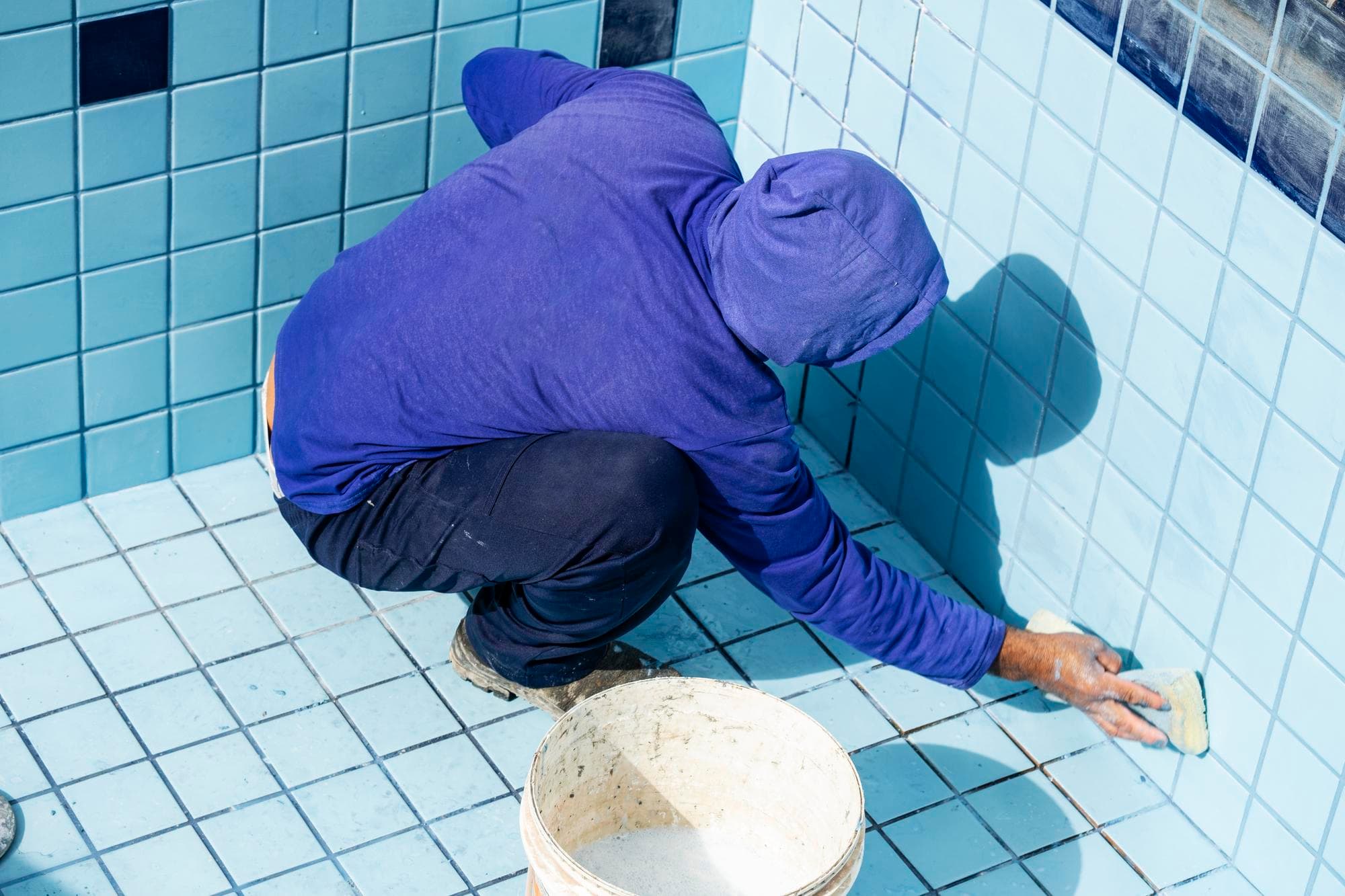 Worker applying waterproofing to bathroom tiles, Gold Coast standards.