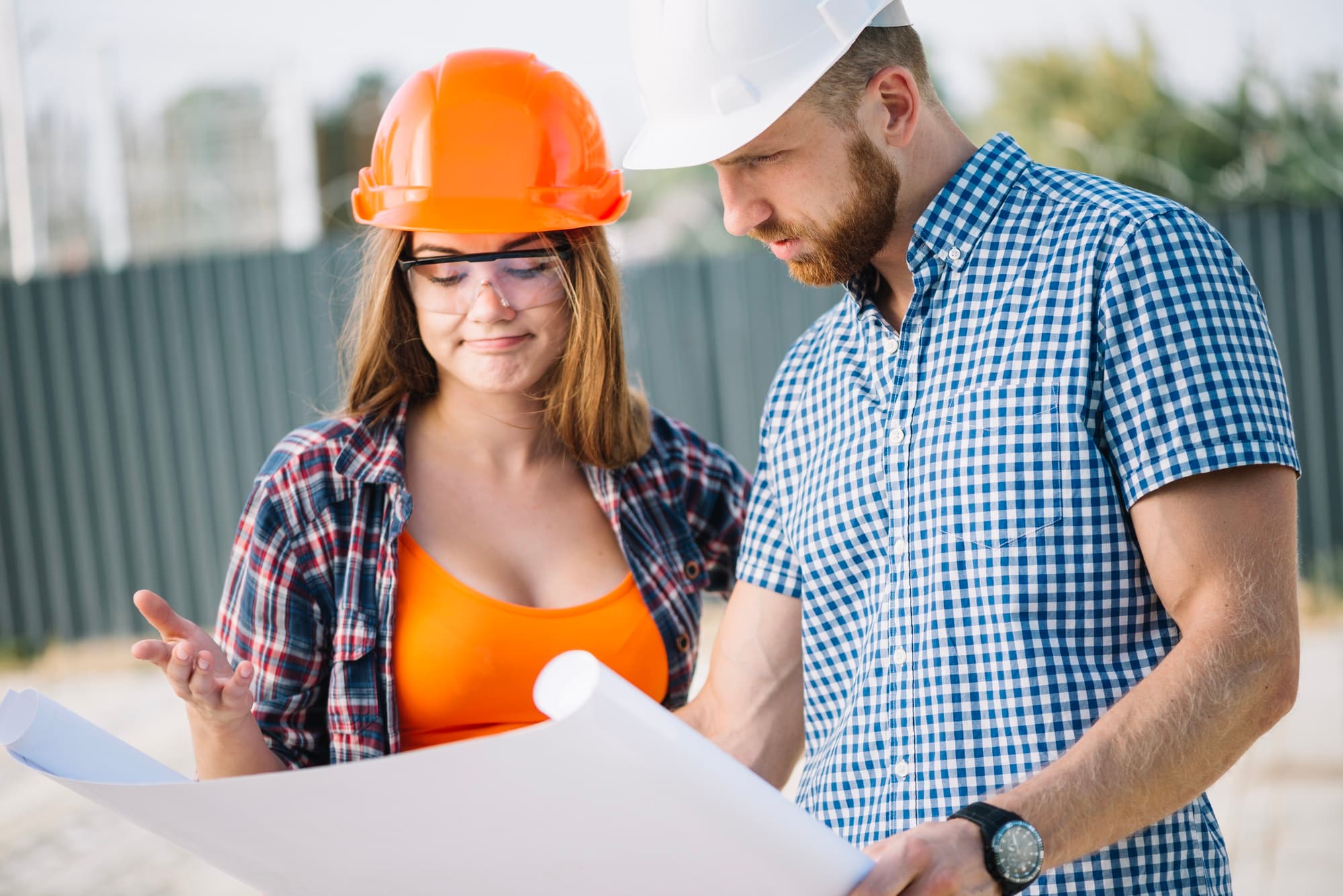 Two people discussing blueprints at a construction site, related to owner builder permit in Queensland.