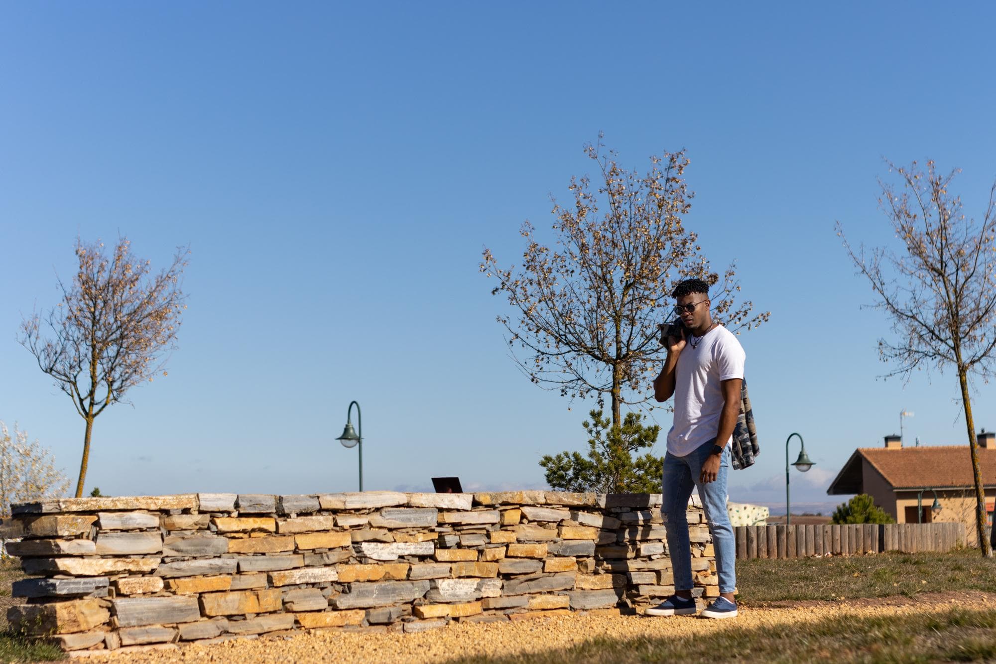 Man standing by a retaining wall on a Queensland boundary with clear sky.